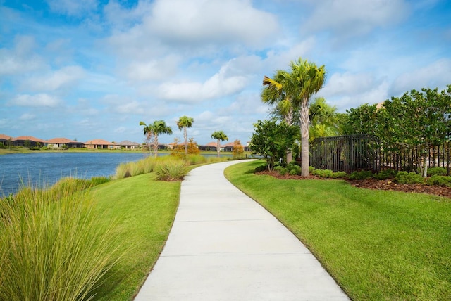 view of home's community featuring a water view, a yard, and fence