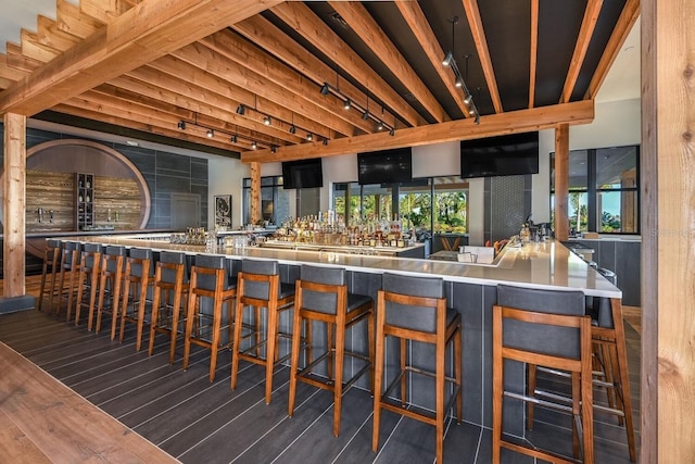 bar featuring track lighting, wood finished floors, and beamed ceiling