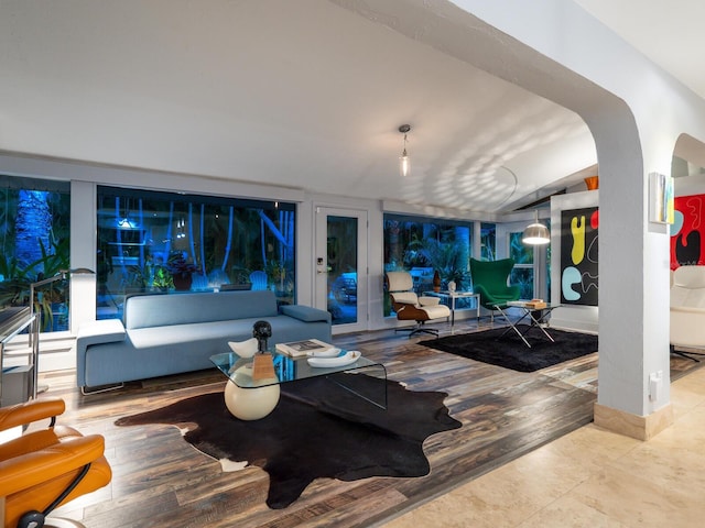 living room with arched walkways, baseboards, and wood finished floors