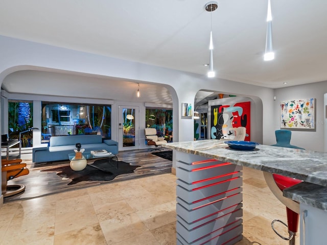 kitchen featuring open floor plan, stone counters, and arched walkways