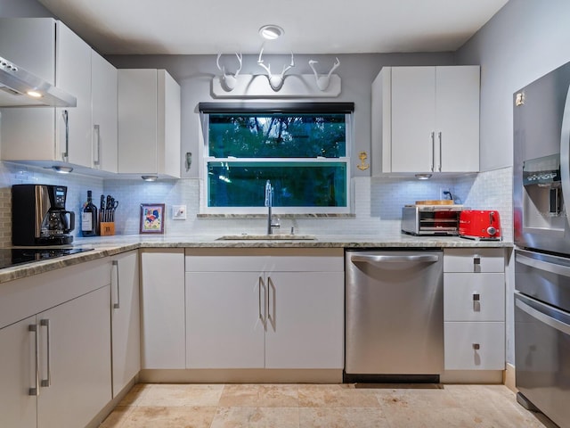 kitchen featuring backsplash, appliances with stainless steel finishes, white cabinetry, a sink, and exhaust hood