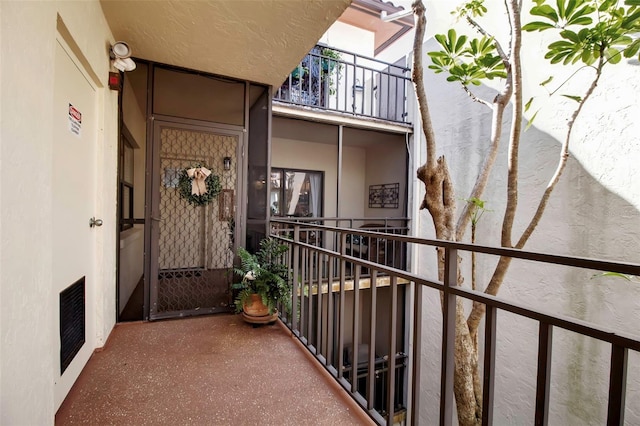 entrance to property with visible vents, a balcony, and stucco siding