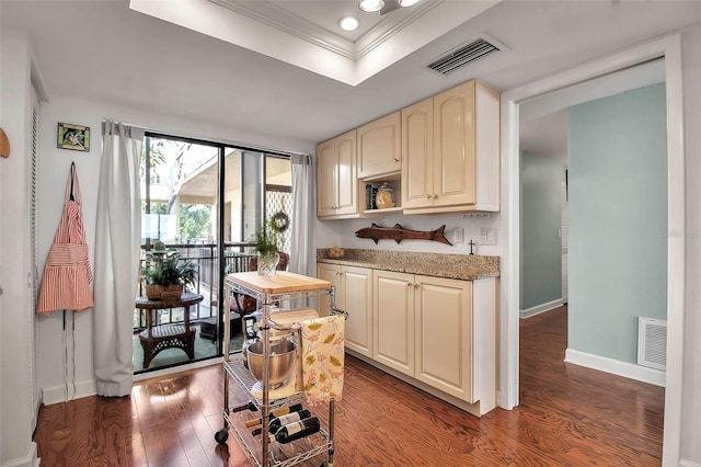 kitchen featuring a tray ceiling, visible vents, baseboards, and wood finished floors