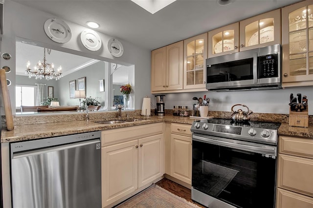 kitchen featuring appliances with stainless steel finishes, a sink, glass insert cabinets, and crown molding