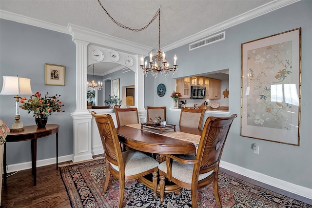 dining room featuring arched walkways, crown molding, wood finished floors, visible vents, and ornate columns