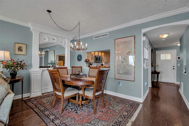 dining room with a textured ceiling, wood finished floors, visible vents, ornamental molding, and ornate columns