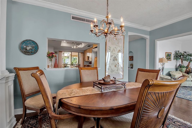 dining area featuring visible vents, arched walkways, ornamental molding, wood finished floors, and a textured ceiling