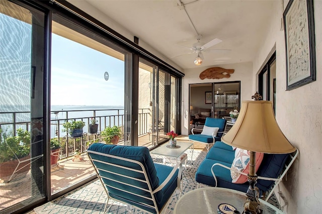 sunroom with a ceiling fan and a water view