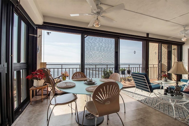 sunroom / solarium featuring a ceiling fan and a water view