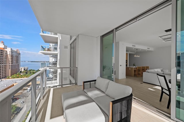 balcony featuring a view of city, a water view, and an outdoor living space