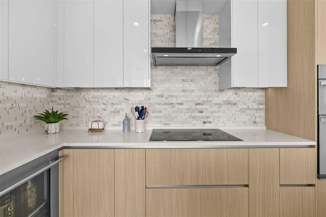 kitchen featuring beverage cooler, wall chimney exhaust hood, light countertops, and black electric cooktop