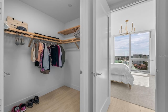 walk in closet featuring light wood-type flooring and a notable chandelier