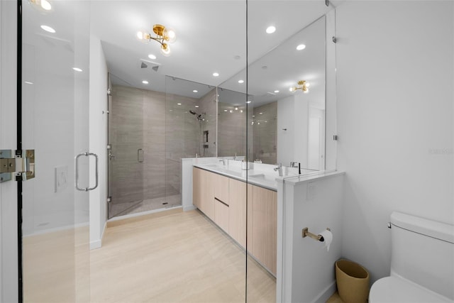 bathroom featuring double vanity, visible vents, toilet, a shower stall, and a sink