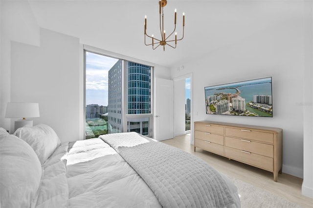 bedroom featuring light wood-style flooring, baseboards, and a notable chandelier