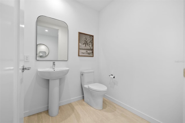 bathroom featuring a sink, toilet, and baseboards