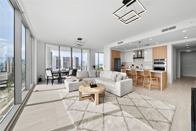 living room featuring expansive windows, visible vents, a view of city, and recessed lighting