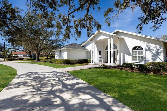 view of front of home featuring driveway, a front lawn, and stucco siding