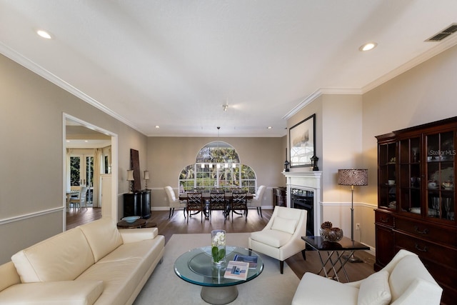 living room with a fireplace, recessed lighting, visible vents, ornamental molding, and wood finished floors