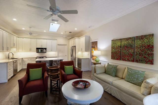 living area featuring a skylight, recessed lighting, visible vents, ornamental molding, and wood finished floors