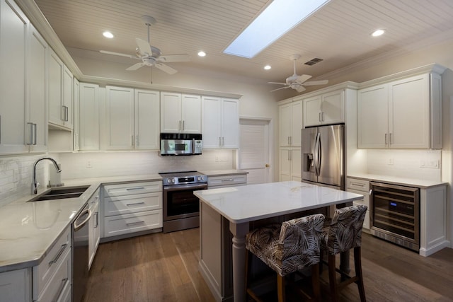 kitchen with wine cooler, stainless steel appliances, a skylight, a sink, and visible vents