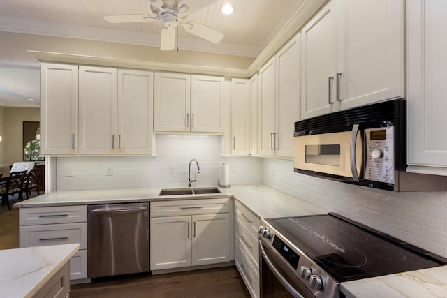 kitchen with light stone countertops, ornamental molding, stainless steel appliances, and a sink