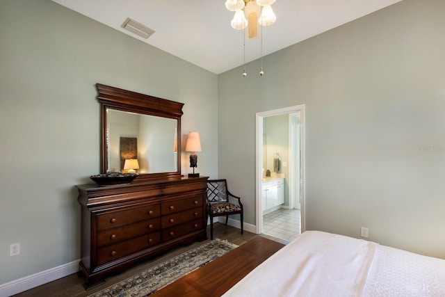 bedroom featuring visible vents, ensuite bath, baseboards, and wood finished floors