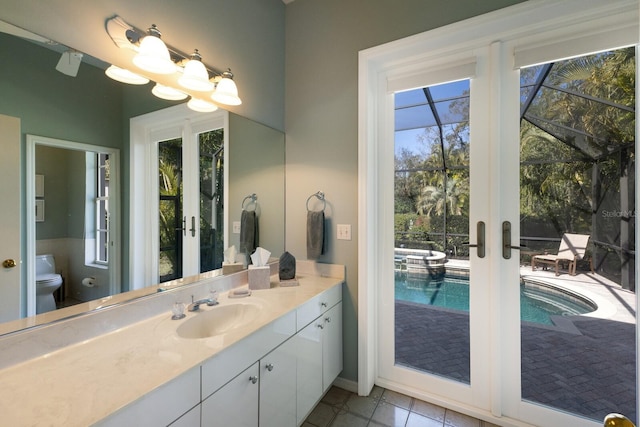 bathroom featuring toilet, tile patterned floors, french doors, and vanity