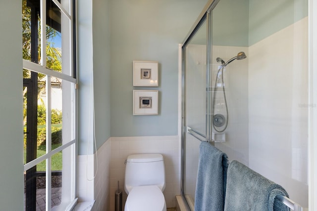 full bath featuring wainscoting, a shower stall, and toilet