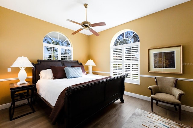 bedroom featuring a ceiling fan, multiple windows, baseboards, and wood finished floors