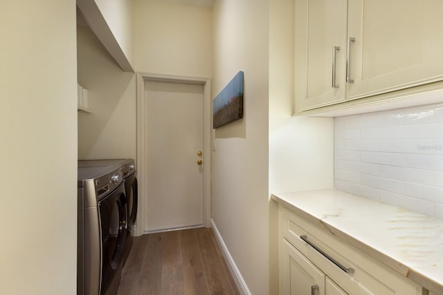 clothes washing area featuring independent washer and dryer, dark wood finished floors, cabinet space, and baseboards