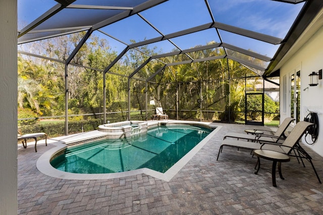 view of pool featuring glass enclosure, a pool with connected hot tub, and a patio area