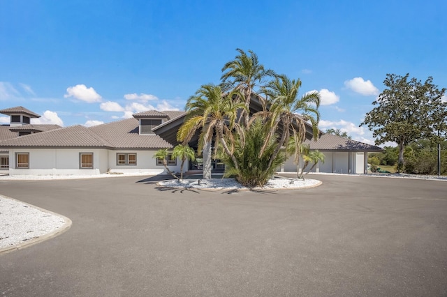 view of front of home featuring driveway, a tiled roof, a garage, and stucco siding