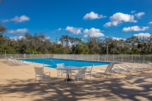 community pool with a patio area and fence