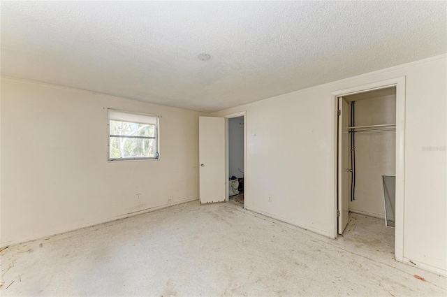 unfurnished bedroom featuring a spacious closet, a textured ceiling, and a closet