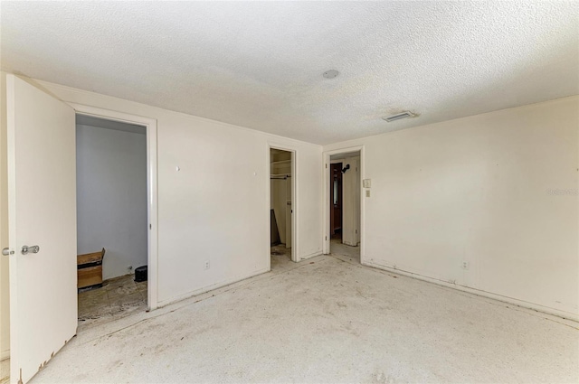 unfurnished bedroom with a walk in closet and a textured ceiling