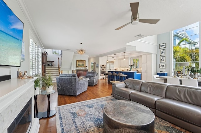 living room with crown molding, dark wood-type flooring, a fireplace, and ceiling fan