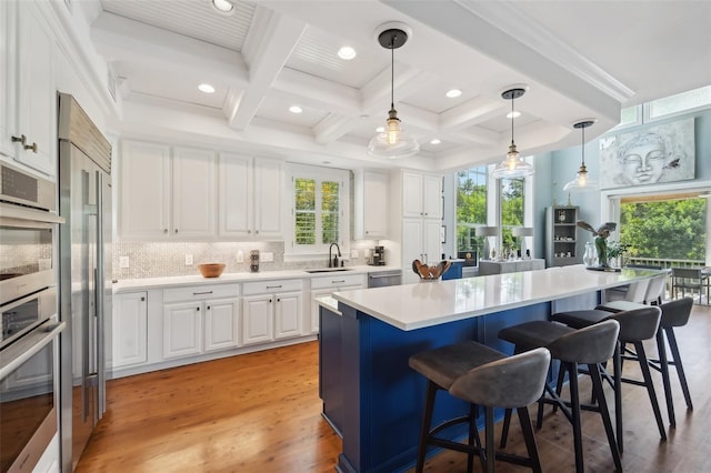 kitchen with a breakfast bar, sink, a kitchen island, and white cabinets