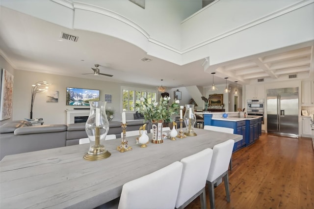 dining area featuring coffered ceiling, ceiling fan, dark wood-type flooring, and beamed ceiling