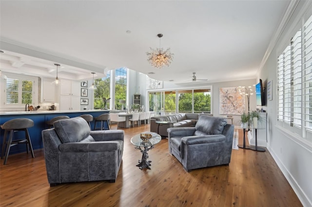 living room with sink, a wealth of natural light, wood-type flooring, and ornamental molding