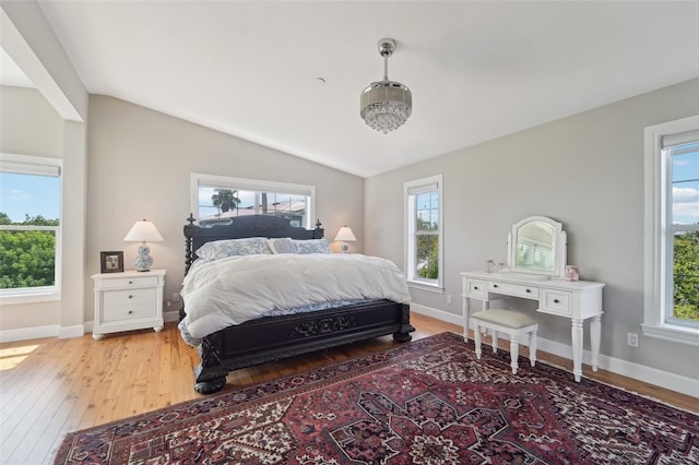 bedroom with multiple windows, wood-type flooring, and lofted ceiling