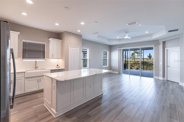 kitchen featuring refrigerator, sink, white cabinets, and a kitchen island