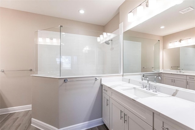 bathroom with tiled shower, vanity, and hardwood / wood-style floors