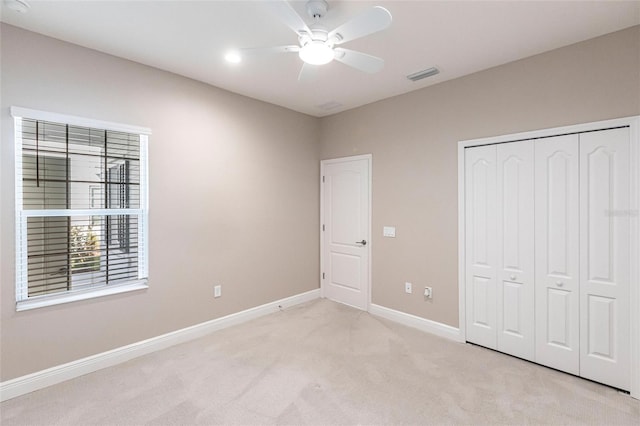 unfurnished bedroom with ceiling fan, a closet, and light carpet