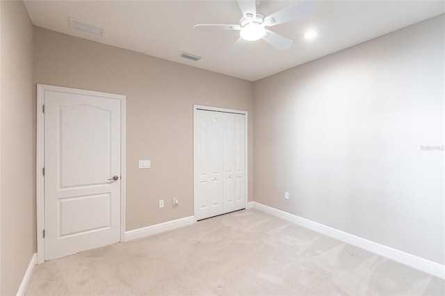 unfurnished bedroom with light colored carpet, a closet, and ceiling fan