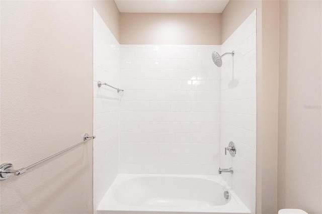 bathroom featuring toilet and tiled shower / bath combo