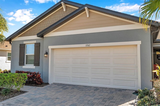 view of front of home featuring decorative driveway, an attached garage, and stucco siding