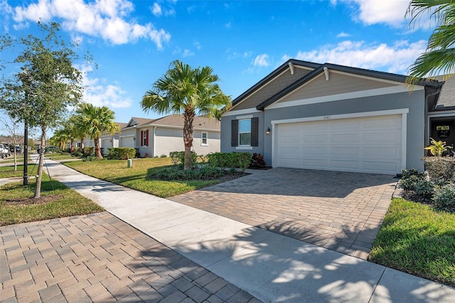 ranch-style home with a garage, a residential view, decorative driveway, a front lawn, and stucco siding