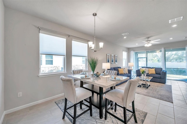 tiled dining room featuring ceiling fan with notable chandelier