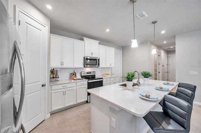 kitchen with stainless steel appliances, sink, a center island with sink, and white cabinets