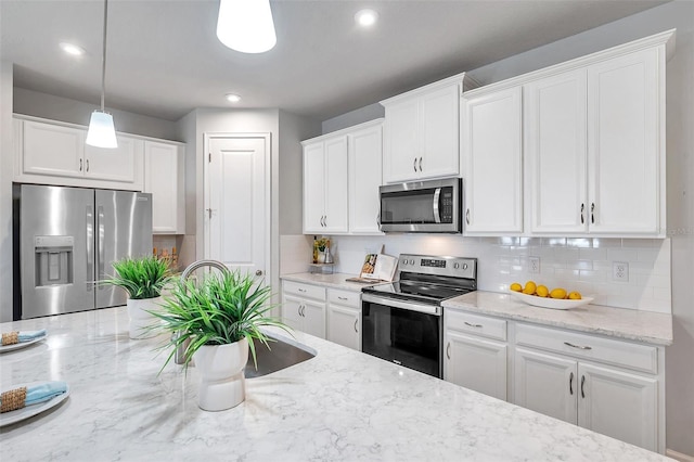 kitchen with tasteful backsplash, light stone counters, decorative light fixtures, stainless steel appliances, and white cabinetry